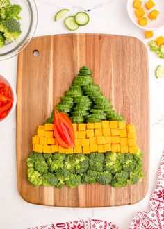 broccoli and carrots arranged in the shape of a house on a cutting board