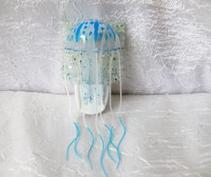 a blue and white jellyfish sculpture sitting on top of a white tablecloth covered bed