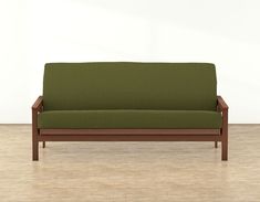 a green couch sitting on top of a hard wood floor next to a white wall