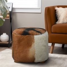 a living room with a brown chair and a cow hide ottoman on the floor in front of a window