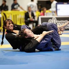 two women in black shirts and blue pants are on the ground with their arms around each other