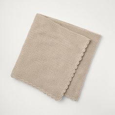 a beige cloth with scalloped edges on a white surface, folded in half