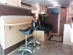 the interior of a camper with two stools and a kitchenette in it