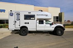 a white truck parked in front of a building with a camper attached to it