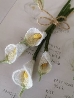 three crocheted flowers tied together on top of a piece of paper with writing in the background