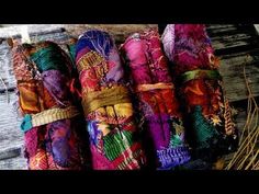 four rolls of colorful fabric sitting on top of a wooden table next to some dry grass