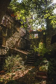 an old stone house surrounded by trees and foliage