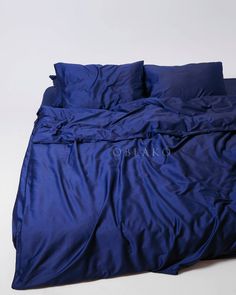 an unmade bed with blue sheets and pillows