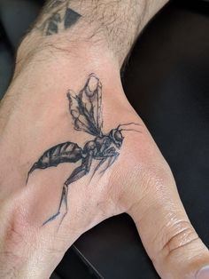 a man's hand with a small insect tattoo on it