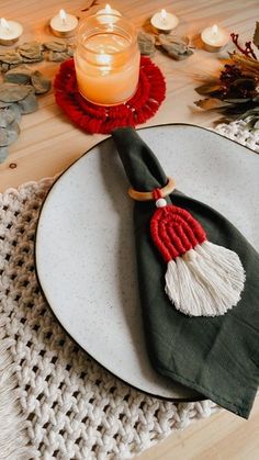 a white plate topped with a green and red napkin next to a candle on top of a wooden table