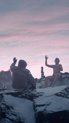 two people sitting on top of a snow covered mountain