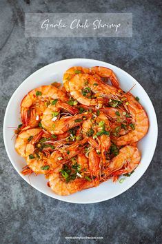 a white bowl filled with cooked shrimp and garnished with parsley on top