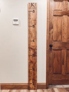 a tall wooden ruler sitting on top of a hard wood floor next to a door