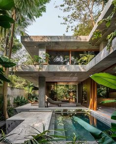 an outdoor pool surrounded by greenery and trees in front of a concrete house with large windows