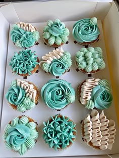 twelve cupcakes in a white box with blue frosting and swirl designs on them