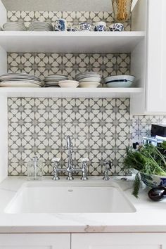 a white kitchen sink sitting under a shelf filled with dishes