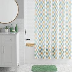 a bath room with a toilet and a shower curtain next to a sink in front of a mirror