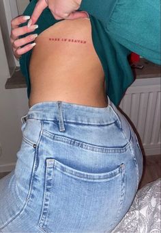 a woman with her back turned to the camera and has a small tattoo on her stomach