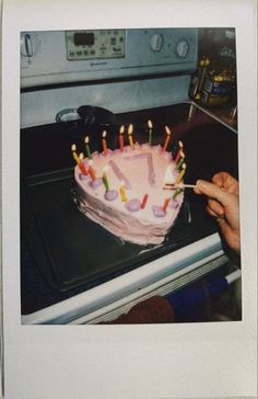 a birthday cake with lit candles on it sitting on top of an oven burner