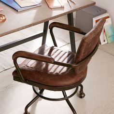 a brown leather chair sitting on top of a wooden desk next to a book shelf