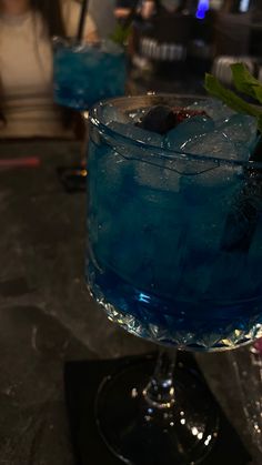 two blue cocktails sitting on top of a table