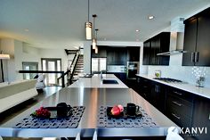 a modern kitchen with stainless steel appliances and black cabinetry, along with stairs leading up to the second floor