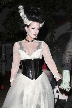 a woman in a white dress and black corset is walking down the street