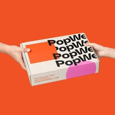 two hands are holding a pop - up box on an orange background