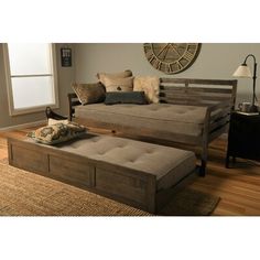 a living room filled with furniture and pillows on top of a wooden floor next to a window