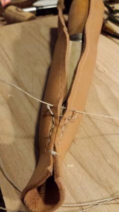 a pair of brown shoes sitting on top of a wooden table next to a knife