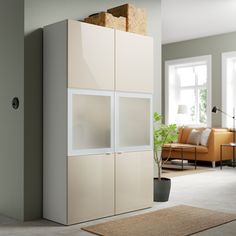 a living room with white furniture and a plant in the corner on top of it