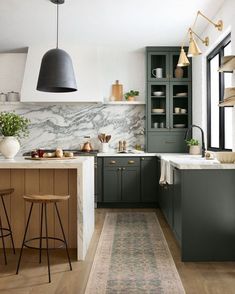 a kitchen with marble counter tops and green cabinets, along with an area rug on the floor