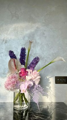 a vase filled with lots of flowers on top of a table next to a wall