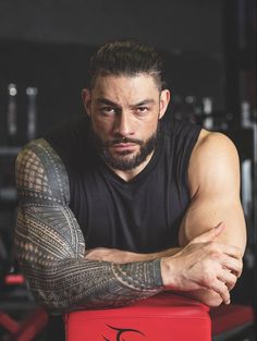 a man with tattoos sitting on top of a red box