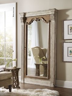 a large mirror sitting on top of a wooden floor next to a chair and table