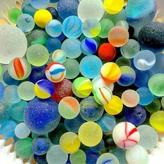 a bowl filled with lots of different colored glass marbles on top of each other