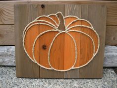 a wooden sign with a rope around it that has a pumpkin on top of it