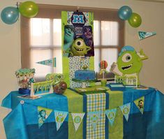 the table is set up with decorations for a monsters birthday party in blue, green and white