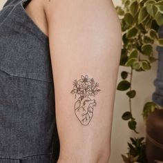 a woman's arm with a heart and flowers tattoo on the left side of her arm