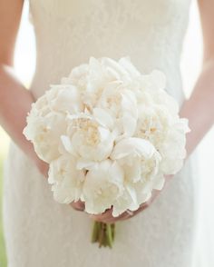 a bride holding a bouquet of white flowers