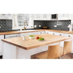 a kitchen with white cabinets and wooden counter tops, along with an island in the middle