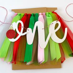 a love sign hanging on a string with some colorful tulle skirtes around it