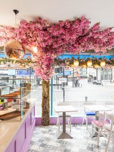 the interior of a restaurant with pink flowers on the ceiling and tables in front of it