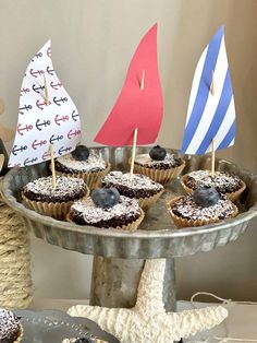 some cupcakes are sitting on a plate with a sailboat and other decorations