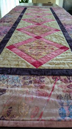 a quilted table top with pink, yellow and purple designs on it's edges