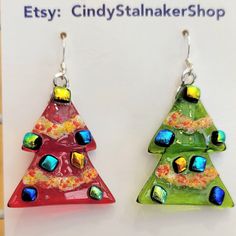 two colorful glass christmas trees hanging from hooks on a white sign that says etsy cidystalanershop