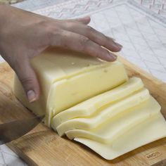 someone is cutting cheese on a wooden board