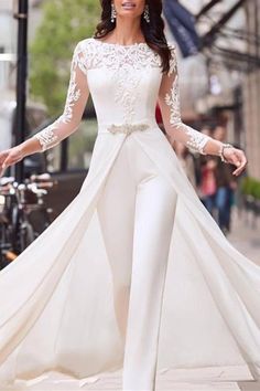 a woman in white is walking down the street wearing a long sleeved wedding dress