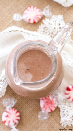 a glass jar filled with chocolate milk sitting on top of a table next to candy canes