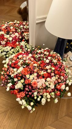 flowers are arranged in the shape of a heart on the floor next to a lamp